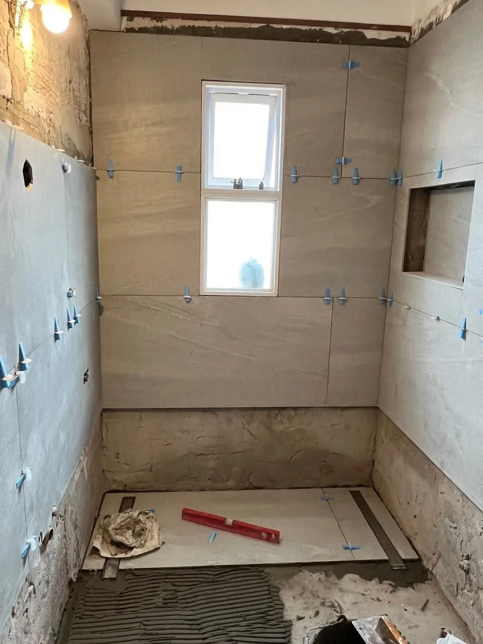 Colocación de revestimientos de gran formato y nicho en un baño en obra