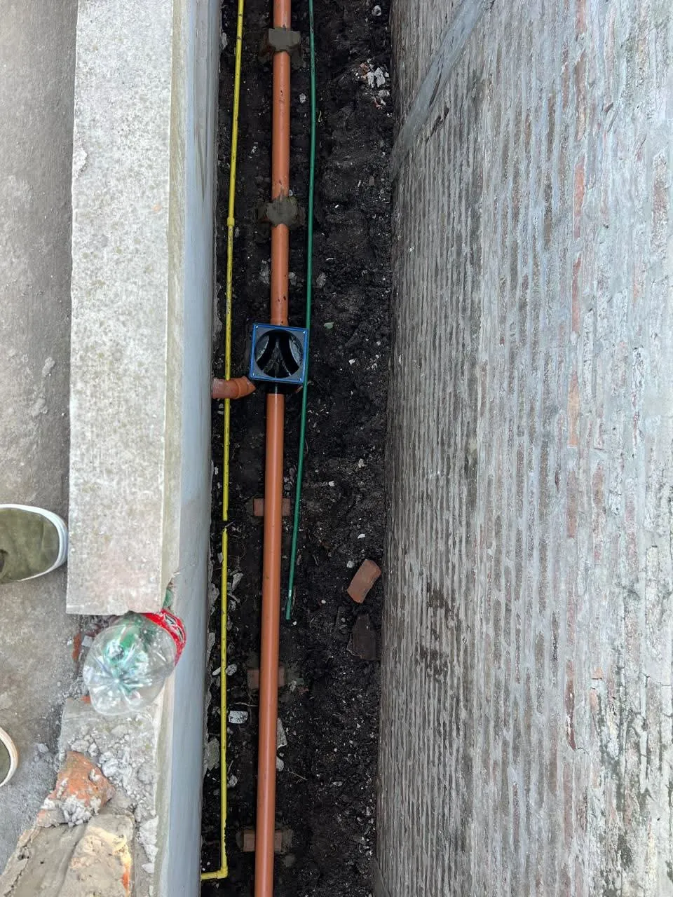 Tendido de cañerías y caja de desagüe en el pasillo lateral entre dos paredes