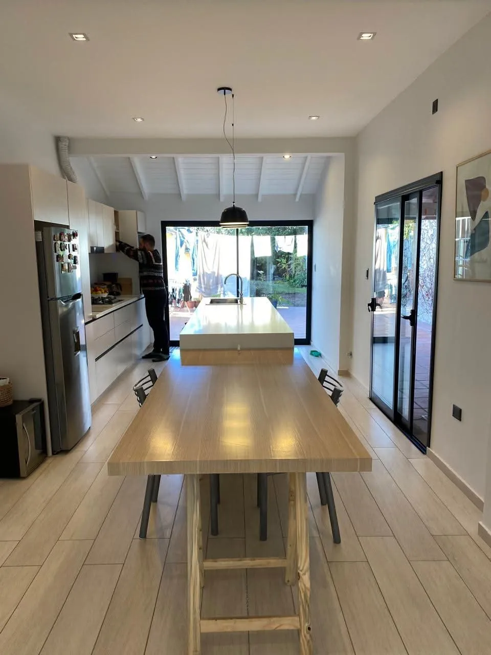 Cocina con isla y mesa de madera integradas, ventanales y muebles claros